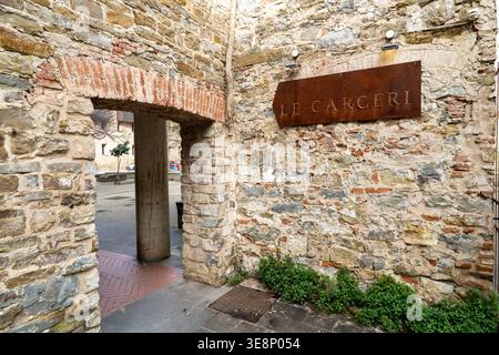 Ein verwitterter Steinbogen führt in einen malerischen europäischen Innenhof mit einem rustikalen Schild über dem Haus Stockfoto