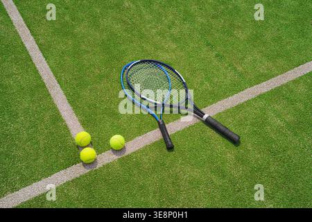 Ein gelber Tennisball und Tennisschläger liegen auf dem Tonplatz. Stockfoto