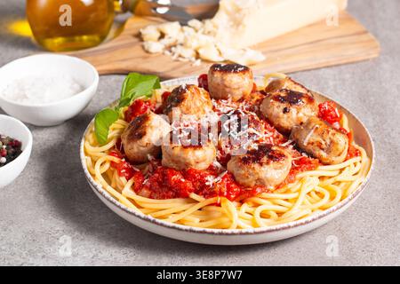 Ein Teller mit klassischen Spaghetti, garniert mit gebräunten Fleischbällchen und reichhaltiger Tomatensauce auf einem leichten Keramikgericht. Stockfoto