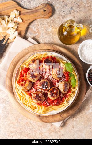 Ein Teller mit klassischen Spaghetti, garniert mit gebräunten Fleischbällchen und reichhaltiger Tomatensauce auf einem leichten Keramikgericht. Stockfoto