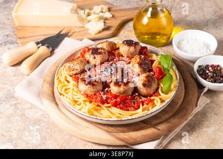 Ein Teller mit klassischen Spaghetti, garniert mit gebräunten Fleischbällchen und reichhaltiger Tomatensauce auf einem leichten Keramikgericht. Stockfoto