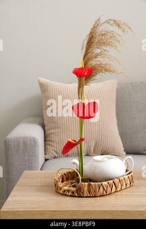 Wunderschönes Ikebana mit Teekanne auf dem Tisch im Wohnzimmer Stockfoto