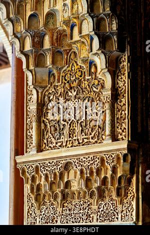 Besucher sehen detaillierte Wandschnitzereien und Bögen in der Alhambra in Granada. Die Architektur zeigt historische Einflüsse und künstlerische Fähigkeiten. Stockfoto