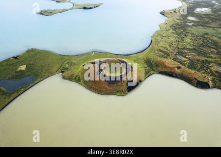 Aus der Vogelperspektive treffen sich kontrastierende türkisfarbene und beige Gewässer an den grünen Ufern in der Nähe eines Vulkankraters und schaffen eine ätherische Landschaft, Skutustadagig Stockfoto
