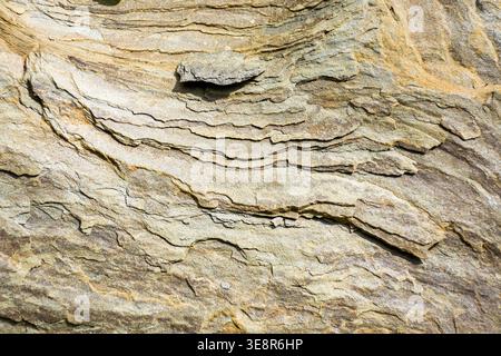 Grunge-Textur von gelblichem grauen Stein. Natursteinhintergrund im Freien aufgenommen. Gealterte Mattmuster aus Sandstein mit subtilen Rissen Stockfoto