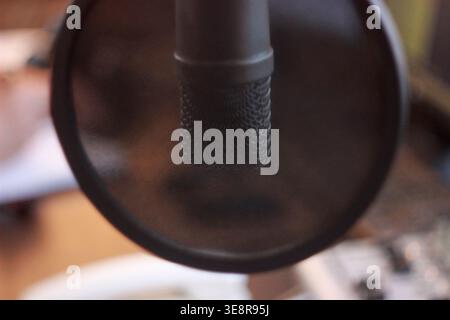 In einem Radiostudio befindet sich ein Mikrofon, das für eine Übertragung bereit ist. Die Audioanlage ist in der Nähe sichtbar. Der Schwerpunkt liegt auf der Audioaufnahme für die Übertragung. Stockfoto