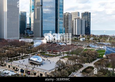 Chicago, USA - 16. April 2025: Menschen, die Cloud Gate Skulptur im Millennium Park, Chicago, genießen, umgeben von modernen Wolkenkratzern und Lake Michigan VI Stockfoto