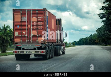 Truck, der roten Frachtcontainer auf offener Autobahn transportiert Stockfoto