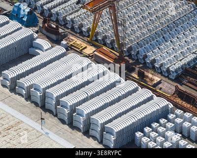 Luftaufnahme von Reihen von gestapelten Betontunnelsegmenten und einem großen orangen Portalkran an einem Industriestandort Taiwan. Stockfoto