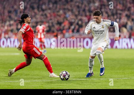 MÜNCHEN – 15. APRIL: Serge Gnabry (FC Bayern München, 7) und Federico Valverde (Real Madrid, 8) kämpfen um den Ball während des UEFA Champions League-Spiels zwischen FC Bayern München und Real Madrid in der Allianz Arena am 15. April 2026 in München. Stockfoto