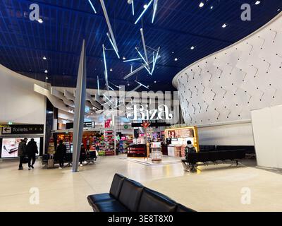 Manchester, Großbritannien - 06. März 2026: Passagiere durchstöbern Duty-Free-Geschäfte und warten in einem modernen Manchester Flughafenterminal unter dramatischer Beleuchtung. Stockfoto