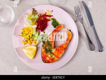 Geröstetes Lachssteak mit grüner Sauce, Gemüse und Zitrone Stockfoto