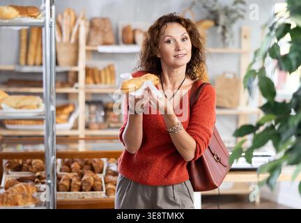 Fröhliche Frau, die frisches Bocadillo in der Bäckerei hält Stockfoto