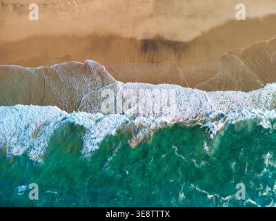 Aus der Vogelperspektive auf Playa del Confital mit türkisfarbenen Meereswellen, die auf goldenen Sand mit weißem Meeresschaum in Las Palmas, Kanarischen Inseln, Spanien stürzen. Stockfoto
