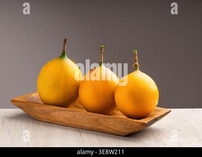 Drei reife, leuchtend orange Granadillas, eine exotische tropische Frucht, präsentiert in einem Studio mit sanfter Beleuchtung - Passiflora ligularis Stockfoto