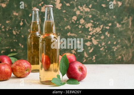 Flaschen mit frischem Apfelwein und Obst auf weißem Tisch Stockfoto