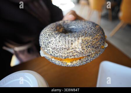 Genießen Sie einen Bagel in einem Café an einem hellen Morgen Stockfoto