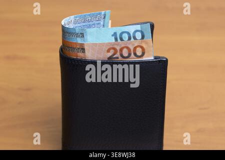 Gambische Geld - Dalasi in der schwarzen Brieftasche Stockfoto