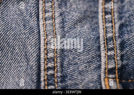 Blaue Jeans-Nahtdetails – Makroaufnahmen mit gezerknitterter Stoffstruktur und weichem, unscharfem Hintergrund Stockfoto