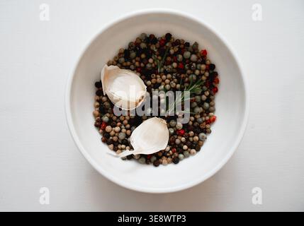 Natürliche Immunität verstärkende Zutaten Knoblauch Rosmarin und Pfeffer Mischung in minimalistischer Schüssel Zusammensetzung Stockfoto