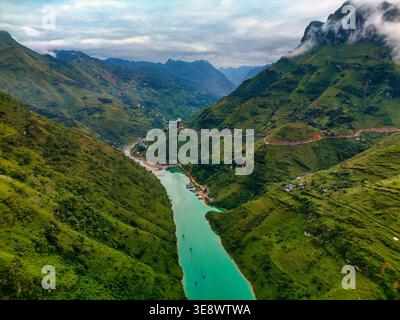 Blick aus der Vogelperspektive auf den türkisfarbenen Nho Que Fluss, der durch den tiefen Ma Pi Leng Pass Canyon fließt, und üppige grüne Terrassenberge im Ha Giang Loop Hoan Stockfoto