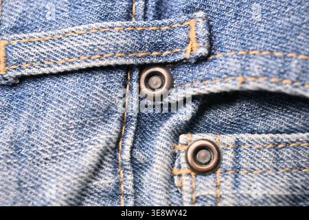 Blaue Denim-Jeans auf der Rückseite mit Knöpfen und Gürtelschlaufen – Nahaufnahme mit Faltenstruktur und weiche, unscharfe Hintergründe Stockfoto