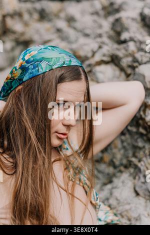Frau Kopftuch Natur Junge schöne Frau, die ein florales Kopftuch trägt, während sie sich vor einem felsigen Hintergrund im Freien posiert Stockfoto