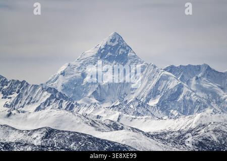 Schneebedeckter Berggipfel im Westen von Sichuan, China, mit einem dramatischen pyramidenförmigen Gipfel, der sich über raues alpines Gelände erhebt. Stockfoto
