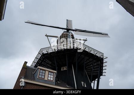 Flacher architektonischer Blick auf Windmill de Adriaan, der sich über einem Backsteingrundstück in Haarlem, Niederlande erhebt und die traditionelle niederländische Windmühle hervorhebt Stockfoto