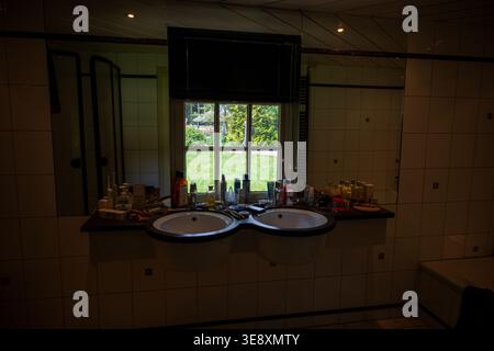 Arnhem, Niederlande - 27. Mai 23: Schwach beleuchtete Badezimmerszene mit Doppelwaschbecken, Spiegel und Toilettenartikeln in einem neu gestalteten Innenraum in den Niederlanden Stockfoto