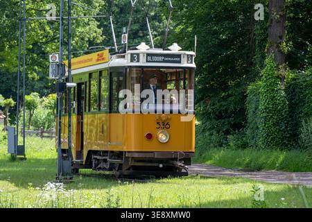 Arnhem, Niederlande - 27. Mai 23: Historische gelbe Straßenbahn auf Gleisen im Niederländischen Freilichtmuseum in Arnhem, Niederlande, mit Freileitungen und Stockfoto