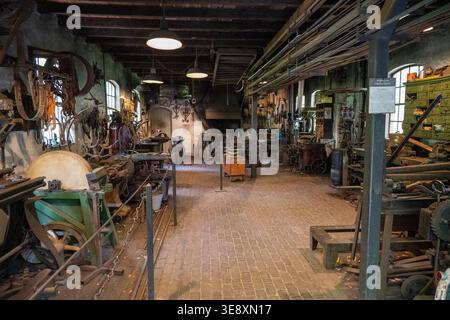 Arnhem, Niederlande - 27. Mai 23: Großes Inneres einer historischen Schmiede mit Werkzeugen, Maschinen und Schmieden im Niederländischen Freilichtmuseum, Arnhe Stockfoto