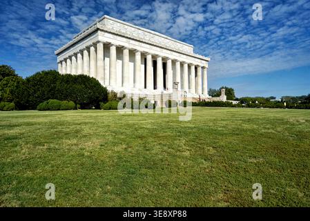 Die Leute laufen um das Lincoln Memorial in Washington D.C. unter einem blauen Himmel mit Wolken. Grünes Gras umgibt das berühmte Gebäude. Stockfoto