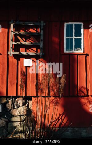 Rustikale alte rote Scheune Holzdiele Wand mit kleinem Fenster mit weißem Hintergrund Stockfoto