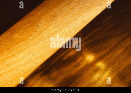 Warmes Sonnenlicht und Schatten auf Holztischoberfläche im Innenraum, natürlicher Texturhintergrund. Konzept: Natürliche Lichtstruktur Stockfoto