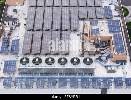 Luftaufnahme von Solarpaneelen und industriellen Kühleinheiten auf einem Gebäudedach mit Rohren und Lüftungssystemen in Taiwan. Stockfoto