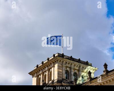 EU-Flagge winkt oben auf der Reichstagsgebäudeecke vor dem dramatischen Himmel, Berlin, Deutschland Stockfoto