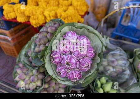 Wunderschöner gefalteter rosa Lotusblütenstrauß, umhüllt in grünes Blatt, ausgestellt am lebhaften lokalen Markt Straßenverkäuferstand, der traditionelle r Stockfoto