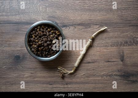 Trockenfutter für Katzen in Metallschale mit Matatabi-Stick-Spielzeug auf hölzernem Hintergrund, Haustierpflegekonzept, Fütterungsroutine, Kopierraum für Branding und Werbung Stockfoto