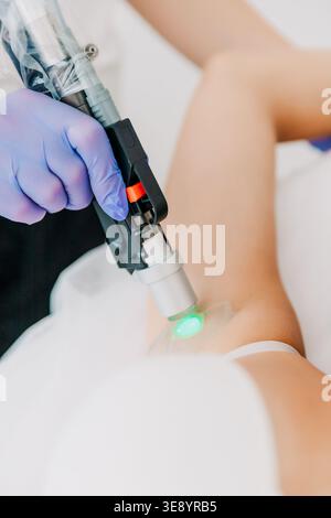 Kosmetologe mit Laser-Haarentfernungsverfahren an junger Frau in der Schönheitsklinik. Ästhetische Medizin, Hautpflege, Körperpflege und professionelle Kosmetik Stockfoto