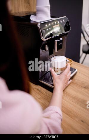 Junge Frau, die Kaffee mit einer Kaffeemaschine zuhause oder in einem Café zubereitete. Lifestyle, morgendliche Routine, Frühstück, Getränkezubereitung und gemütliches Zuhause Stockfoto