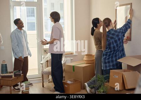 Multiethnische Erwachsene Freunde schmücken nach dem Einzug ein neues Zuhause Stockfoto