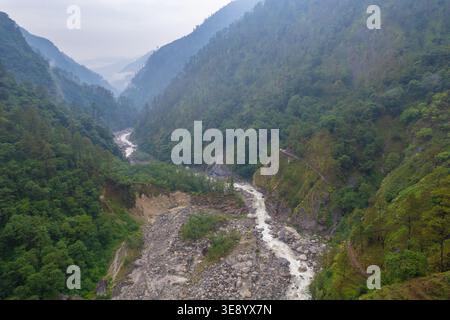 Ein atemberaubender Blick aus der Vogelperspektive auf eine bergige Landschaft mit einem sich windenden Fluss, umgeben von dichtem Grün und rauem Gelände, das die natürliche Umgebung zeigt Stockfoto