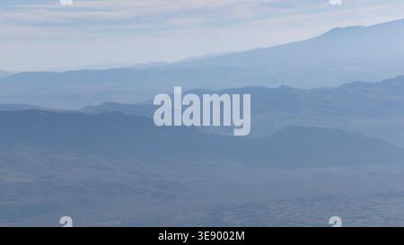 Atemberaubende Aussicht auf nebelige Berge, die am frühen bewölkten Morgen in Nebel gehüllt sind. Stockfoto