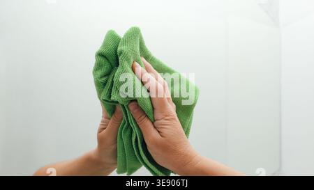 Frau putzt Spiegel mit Lappen im Badezimmer. Housekeeping- und Reinigungsservice. Sauberes Haus. Hand einer Frau mit Tüchern Stockfoto