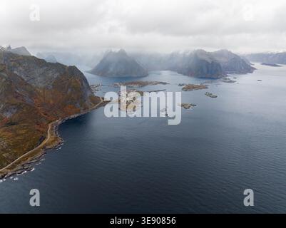 Aus der Vogelperspektive der Lofoten mit dramatischen Berggipfeln unter bewölktem Himmel und kleinen Fischerdörfern, die über den Archipel in Nord verstreut sind Stockfoto