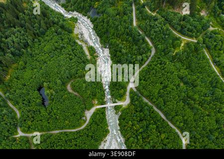 Drohnenblick auf einen Gletscherfluss und Bergwald mit gewundenen Straßen in der Nähe von Grindelwald, Berner Oberland, Schweiz, Schweizer Alpen. Stockfoto