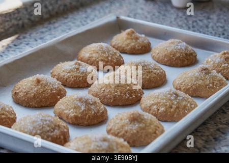 Frisch gebackene Plätzchen mit Zuckerbelag auf einem Backblech mit Backpapier Stockfoto