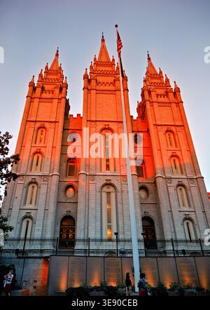 Besucher beobachten den Salt Lake Mormon Tempel, während die Sonne hinter dem historischen Gebäude in Salt Lake City, Utah, untergeht. Stockfoto