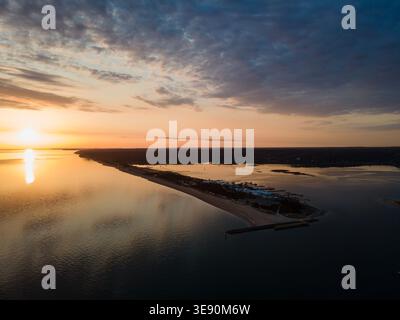 Blick auf den Sonnenuntergang über die Küste von Long Island mit ruhigem Wasser, Yachthafen und Sandbank, die sich bis in die Bucht unter dramatischem Himmel erstreckt Stockfoto